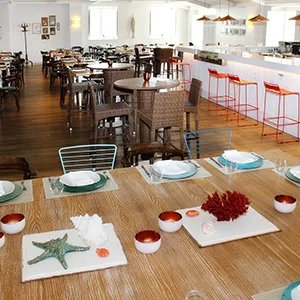 Sal&oacute;n de comedor con mesas servidas y sillas, decoraci&oacute;n oto&ntilde;al.
