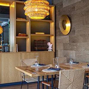 Comedor con mesa y sillas, l&aacute;mpara de techo y estanter&iacute;a de madera.