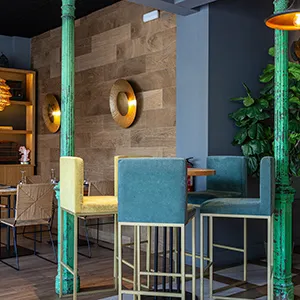 Interior de bar moderno con asientos azules y columnas verdes decorativas.