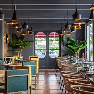 Interior de restaurante con mesas, sillas y l&aacute;mparas colgantes modernas.