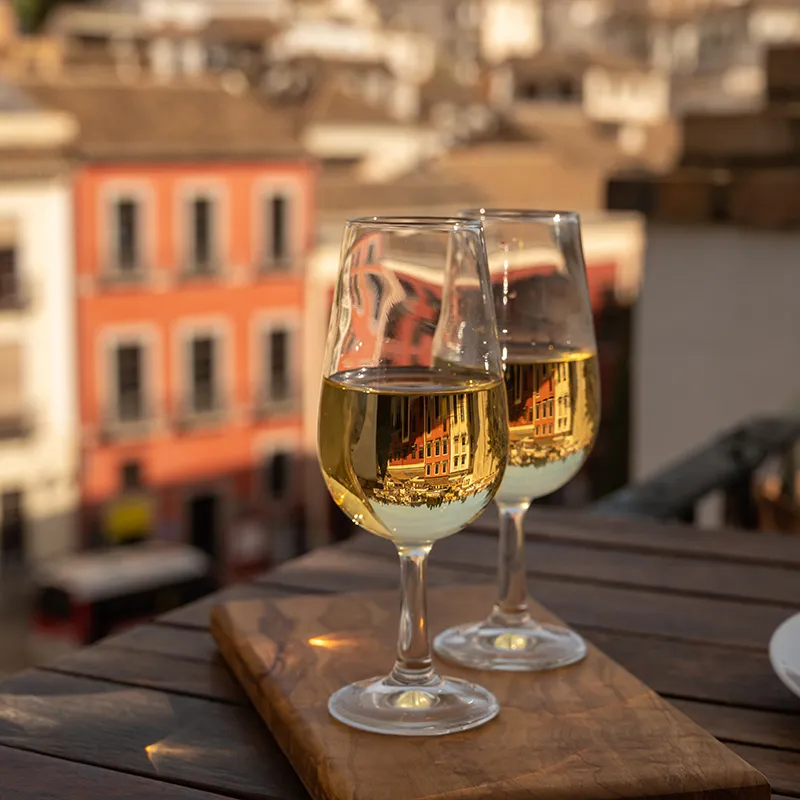 Dos copas de vino reflejando edificios en una terraza soleada