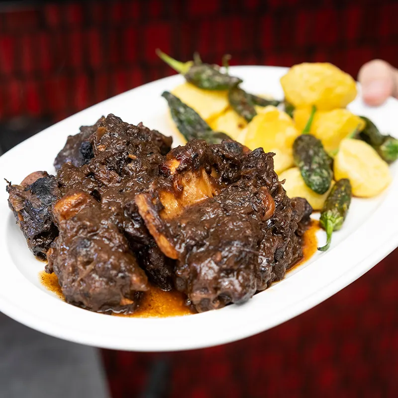 Plato con carne estofada y guarnici&oacute;n de verduras y patatas asadas.