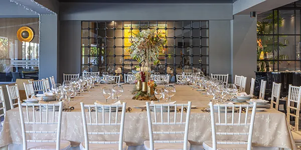 Mesa de banquete con copas y decoraci&oacute;n floral en un sal&oacute;n elegante.