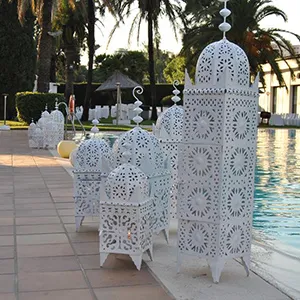 Candelabros y faroles blancos decorativos junto a una piscina al aire libre