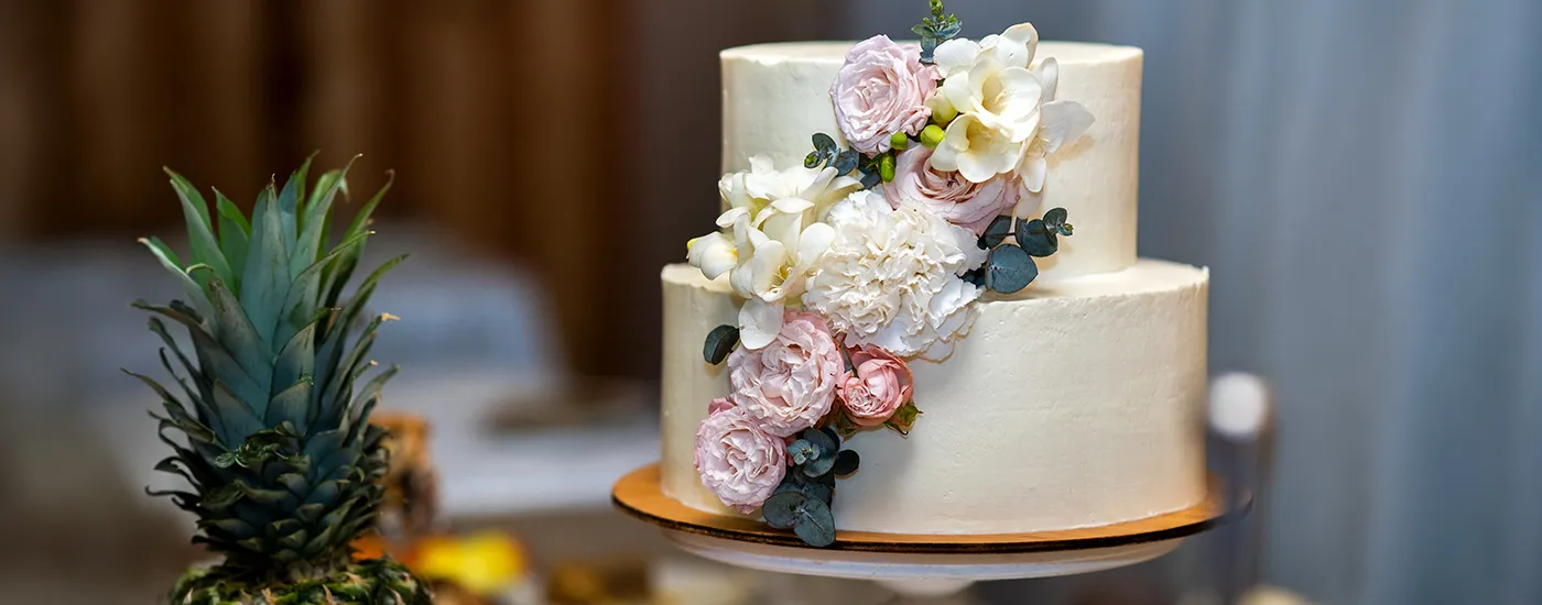 Pastel nupcial blanco con flores de rosas y orqu&iacute;deas, dos pisos y fondo desenfocado