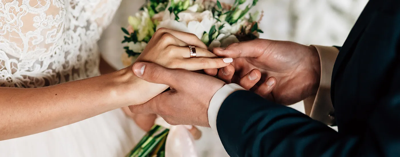 Manos entrelazadas con anillos, ramo y boda en primer plano, brindis emocional