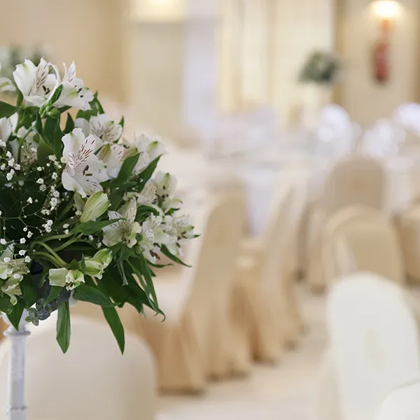 Ramo de flores blancas con fondo de ceremonia en una sala beige.
