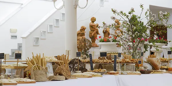 Mesa con panes y dulces artesanales, decoraci&oacute;n de flores y panader&iacute;a.