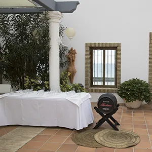 Mesa decorada con coj&iacute;n y farol en patio con plantas y columnas