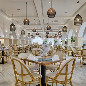 Comedor elegante con mesas, sillas doradas y l&aacute;mparas colgantes.