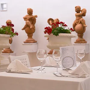 Mesa de banquete con copas, servilletas y estatuas decorativas.