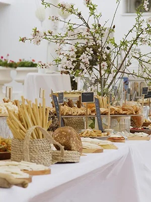 Mesa con pan y bollos, velas y ramas floridas decorando el evento.