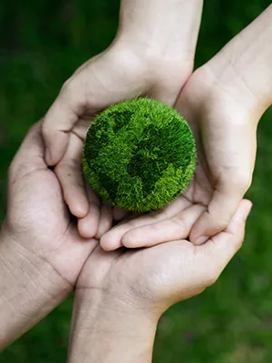 Manos sosteniendo un c&iacute;rculo de musgo verde en un entorno natural