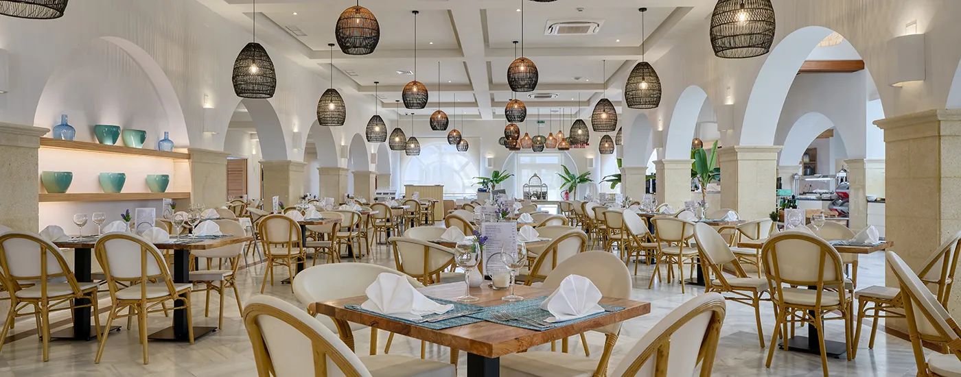 Sal&oacute;n de banquetes con mesas servidas, sillas doradas y l&aacute;mparas colgantes.