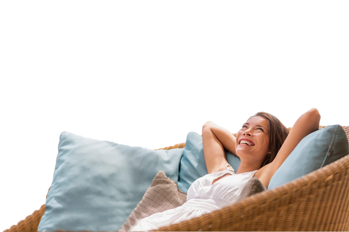 Mujer relaj&aacute;ndose sonriendo en un sof&aacute; con cojines azules sobre fondo negro