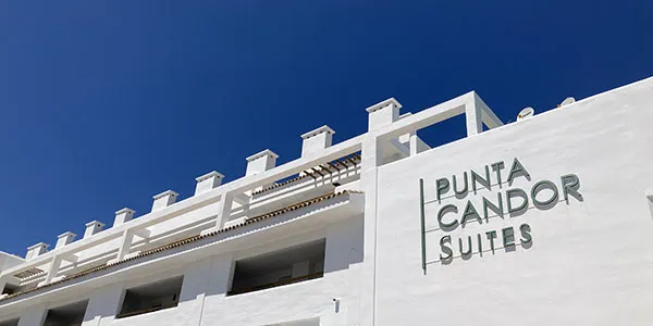 Fachada de hotel con letrero &ldquo;Punta Cando Suites&rdquo; sobre cielo azul