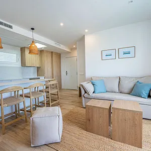 Sala luminosa con sof&aacute;, mesas auxiliares y cocina integrada.