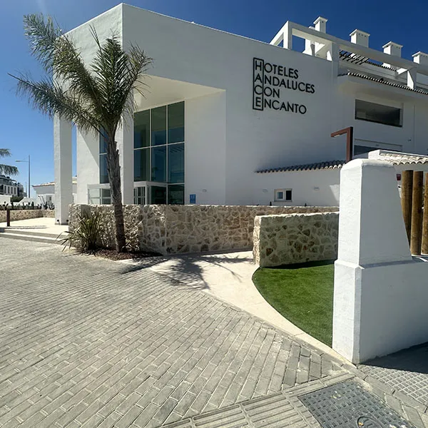 Fachada de hotel blanco con letrero &ldquo;Hoteles Andalucia con encanto&rdquo; y jard&iacute;n.