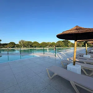 Terraza con piscina al aire libre y caba&ntilde;a de paja bajo el cielo azul