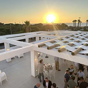 Terraza blanca con invitados bajo el atardecer y el sol al fondo