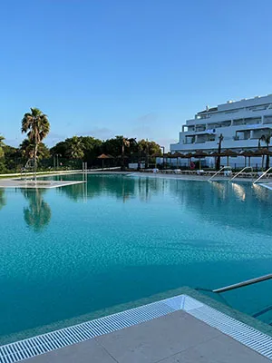 Piscina con agua turquesa y hotel junto al cielo azul