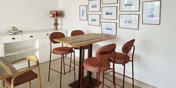Comedor con mesa de madera y sillas altas en ambiente luminoso.