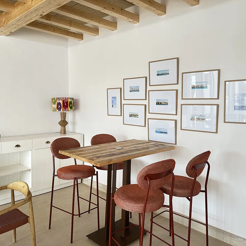 Sala con mesa de madera, sillas rojas y cuadros en la pared, iluminaci&oacute;n moderna.
