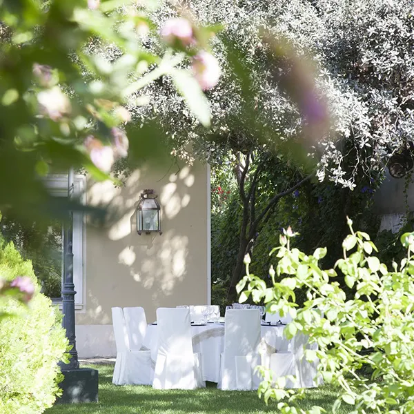 Mesa de banquete con sillas blancas en jard&iacute;n verde y farol de luz