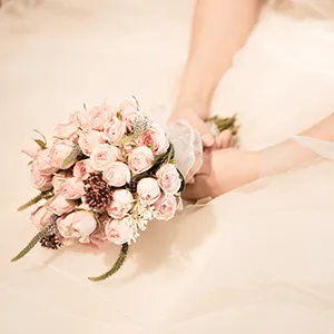Ramo de rosas rosadas en manos de novia con vestido blanco
