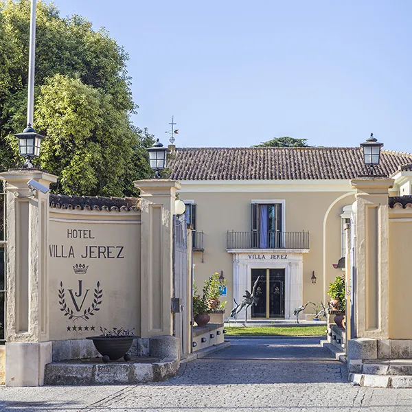 Entrada del Hotel Villa Jerez con letrero y patio.