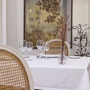 Mesa de banquete con copas y jarr&oacute;n con ramas oto&ntilde;ales decorando el centro.