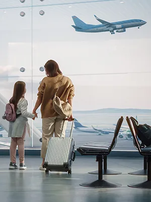 Pasajeros esperan en el aeropuerto frente a un avi&oacute;n despegando.
