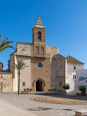 Iglesia de piedra con campanario en un pueblo bajo cielo azul
