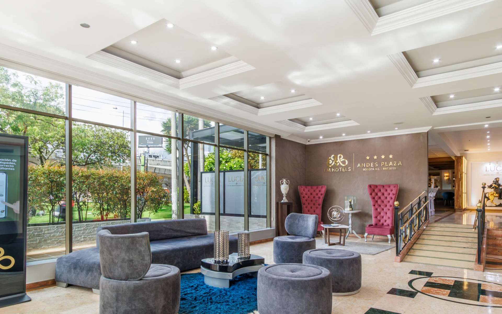 Lobby de hotel con sillones, ventanas grandes y decoraci&oacute;n elegante.