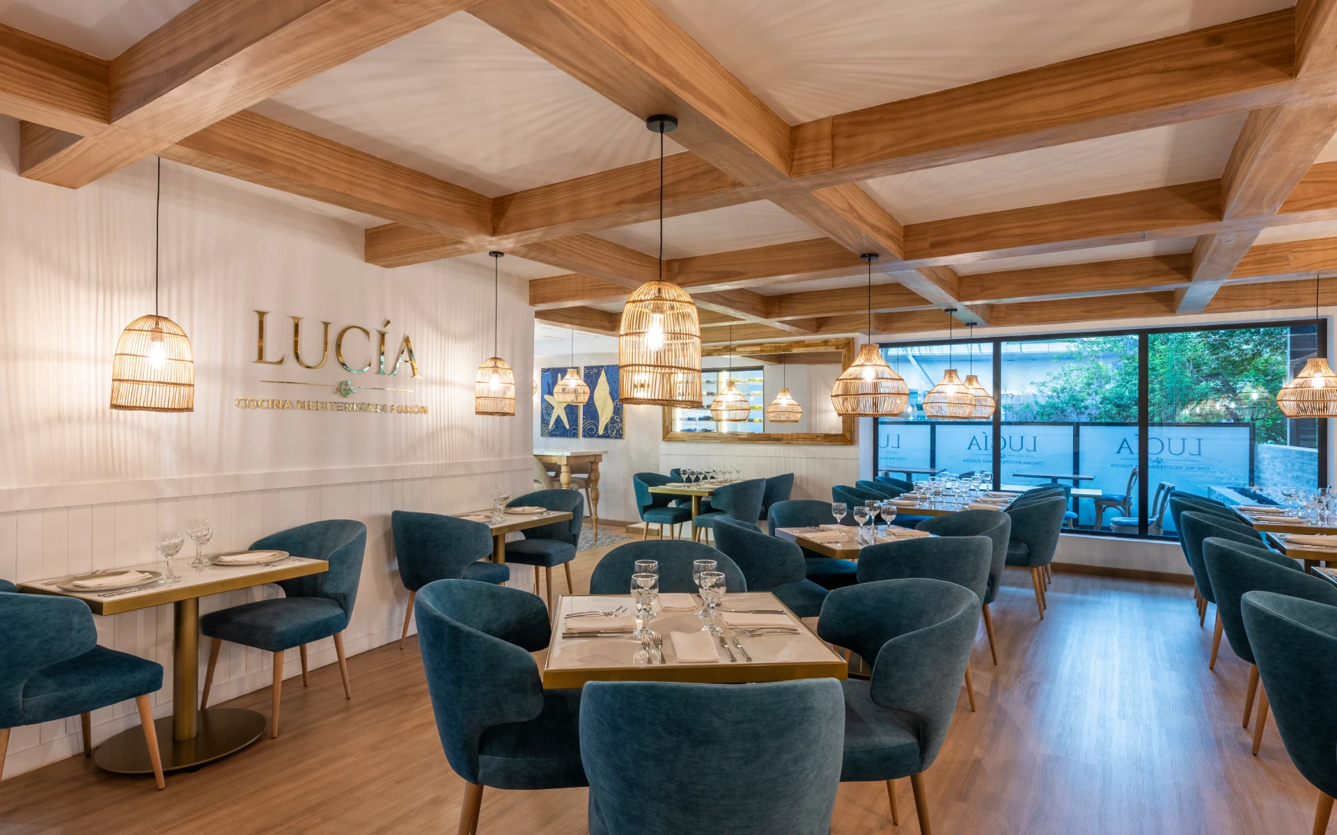 Restaurante elegante con sillas azules y l&aacute;mparas colgantes de mimbre.