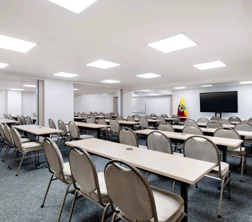 Aula vac&iacute;a con sillas, mesas, TV y una bandera de Ecuador.