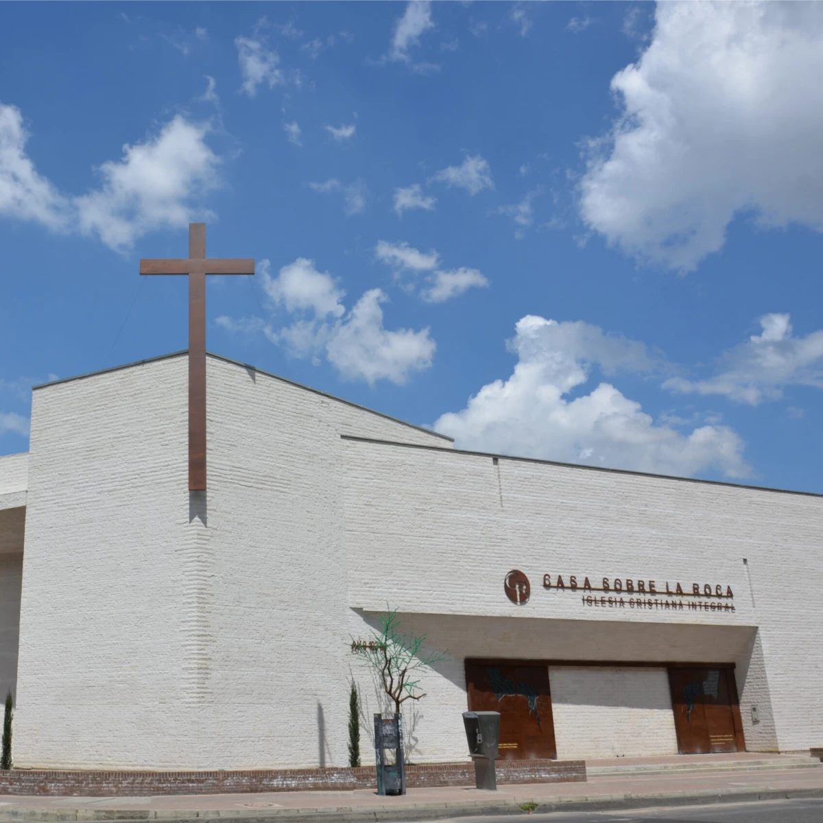Edificio moderno de iglesia cristiana con cruz grande y cielo azul claro.