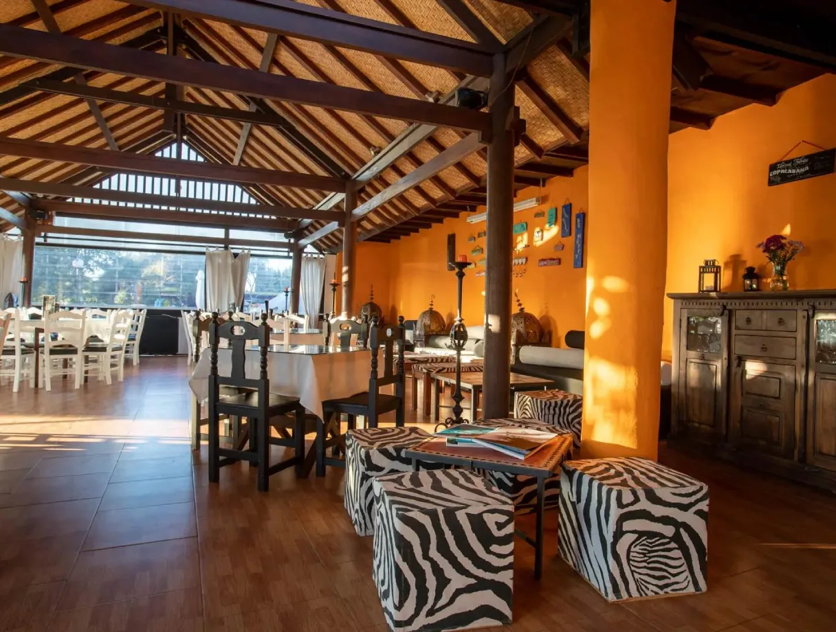 Restaurante de techo alto, paredes naranjas, muebles r&uacute;sticos y decoraci&oacute;n &uacute;nica.