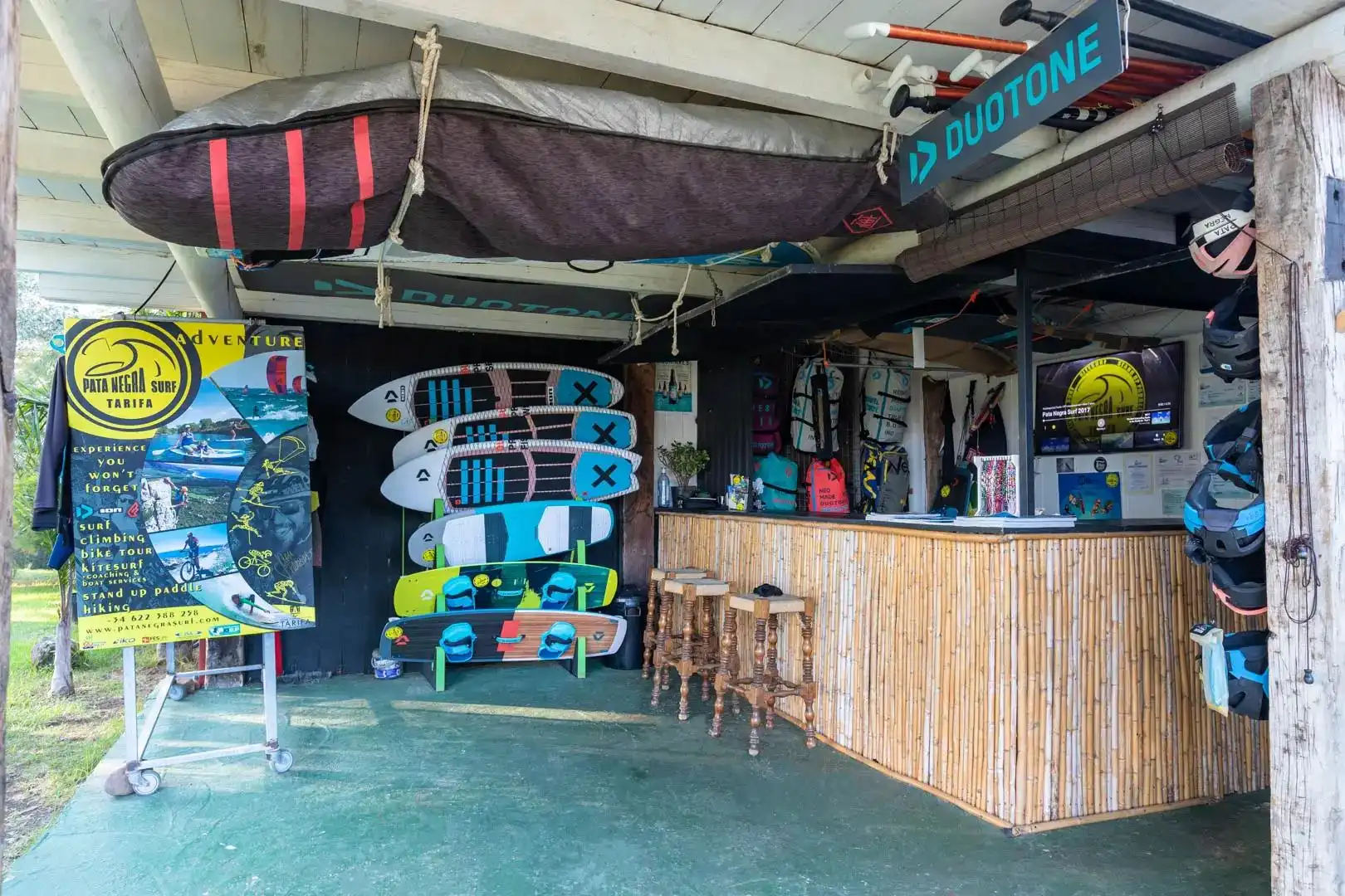 Tienda de surf con tablas, equipo y carteles coloridos en un entorno playero.