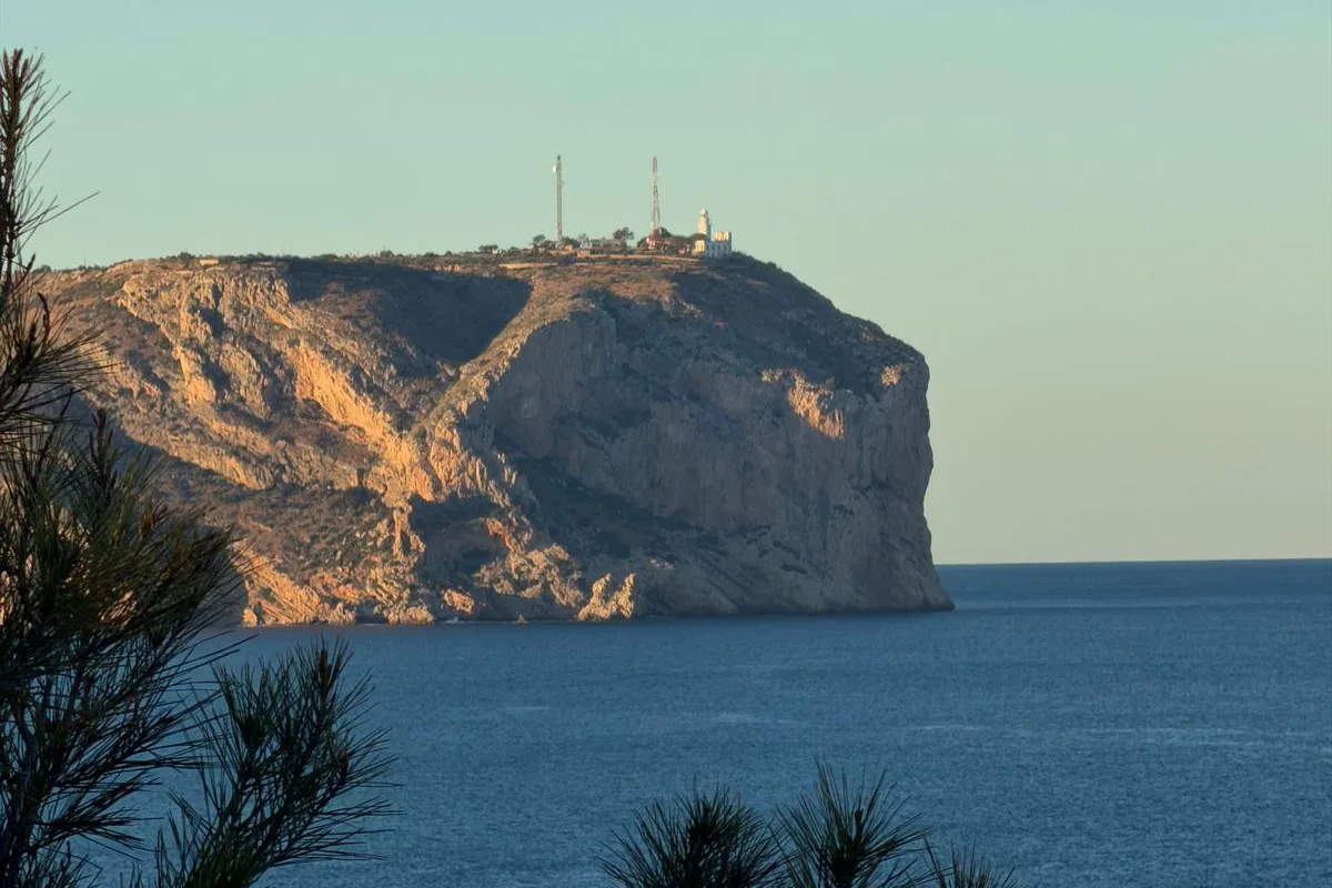 Acantilado rocoso con torre en la cima sobre el mar al atardecer