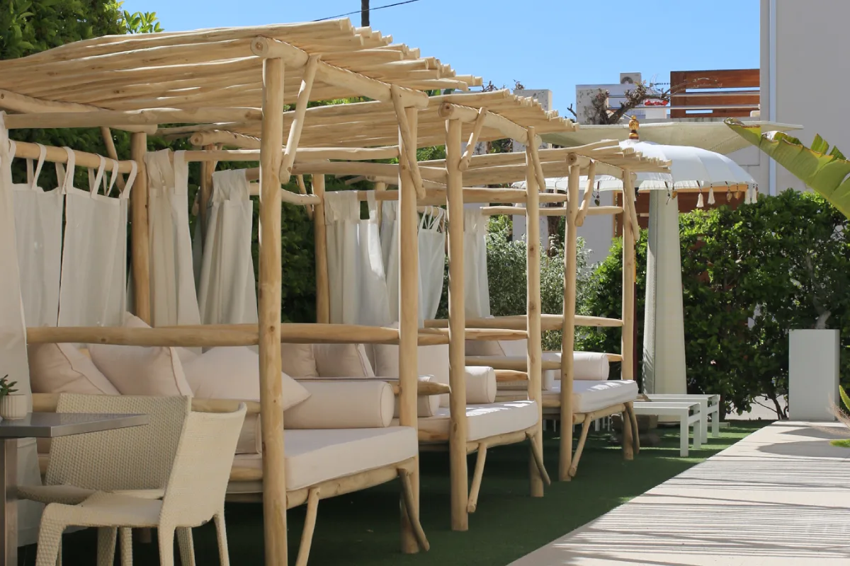 Estructura de madera con cortinas blancas y &aacute;rea de descanso al aire libre