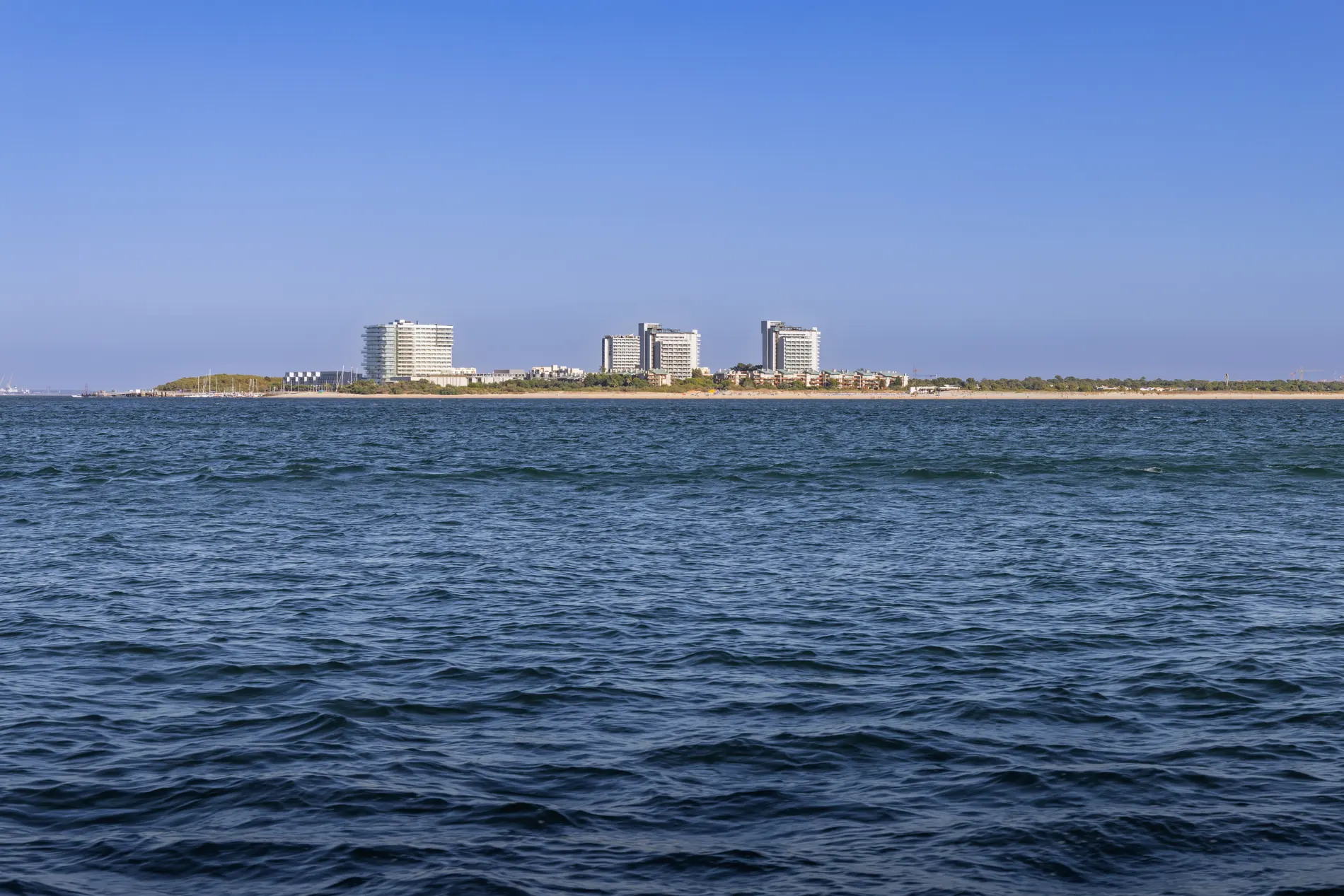 Edif&iacute;cios modernos &agrave; beira-mar em um dia ensolarado com c&eacute;u azul.