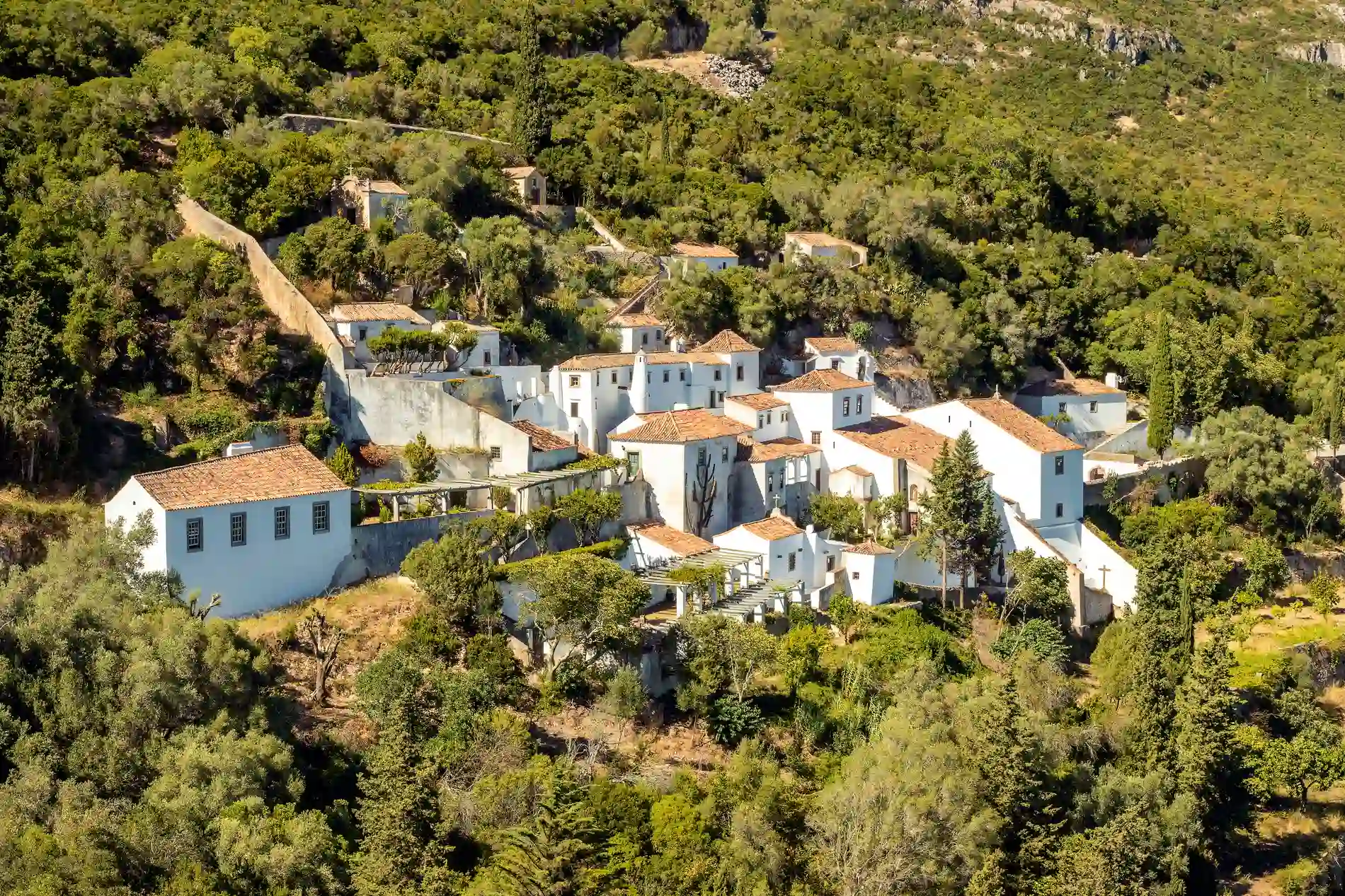 Casas brancas rodeadas por &aacute;rvores em vilarejo montanhoso.