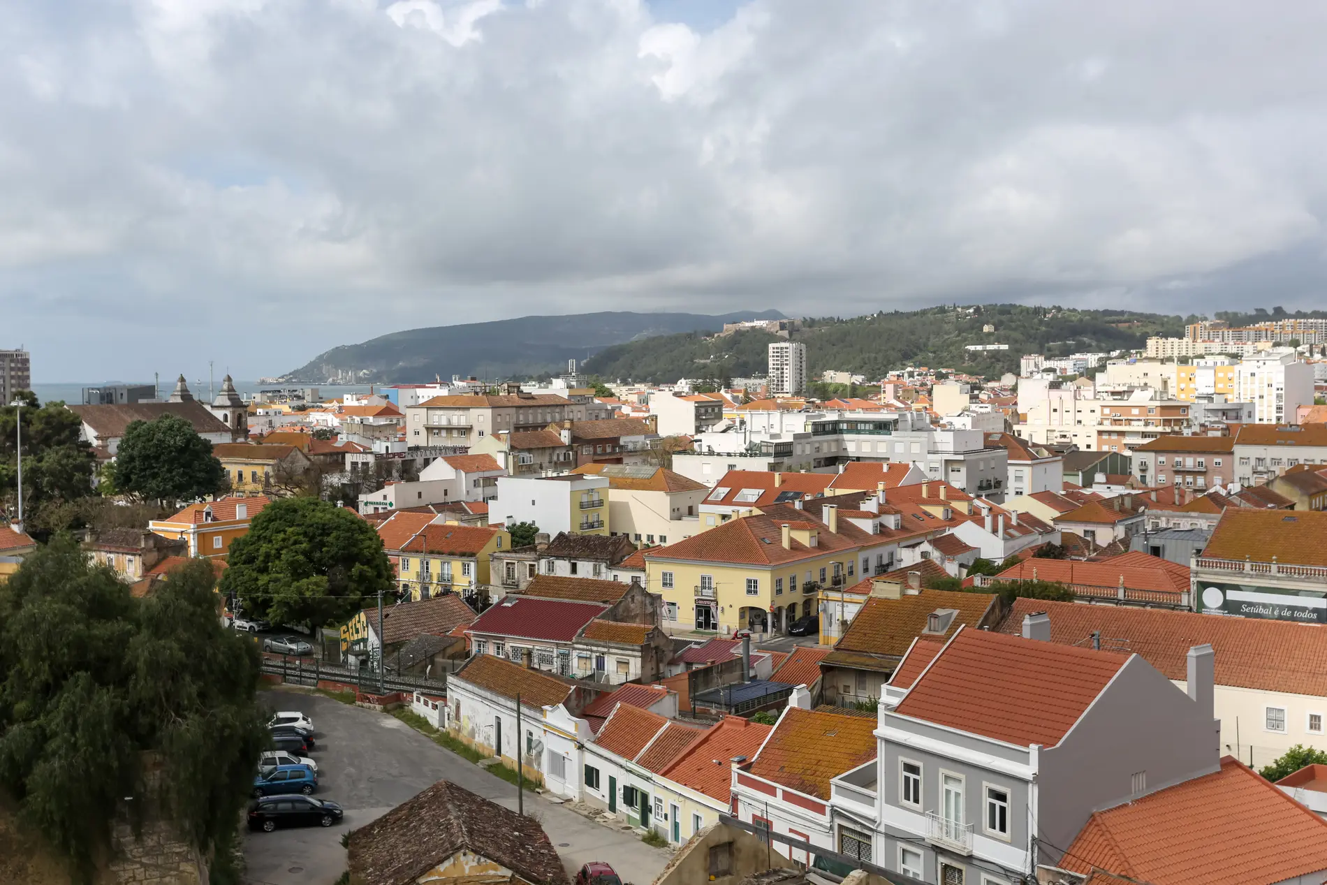 Vista panor&acirc;mica de uma cidade com casas e colinas ao fundo.