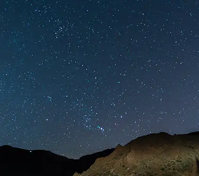 Starry night sky over silhouetted mountains.