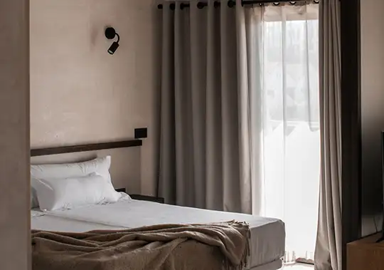 Cozy bedroom with gray curtains and a bed by a window.
