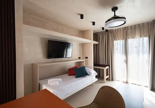 Modern room with TV, sofa, and desk by large windows.