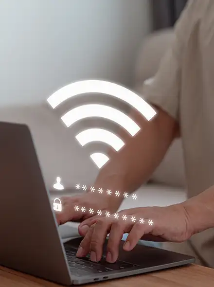 Person typing on a laptop with a Wi-Fi symbol above.