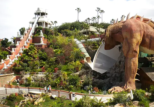 Amusement park with a dragon statue and lush greenery.