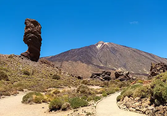 Rock formation with mountain and clear blue sky in the background.
